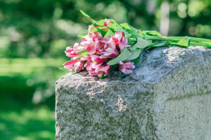 Headstone in cemetery with beautiful fresh tropical flowers resting on top